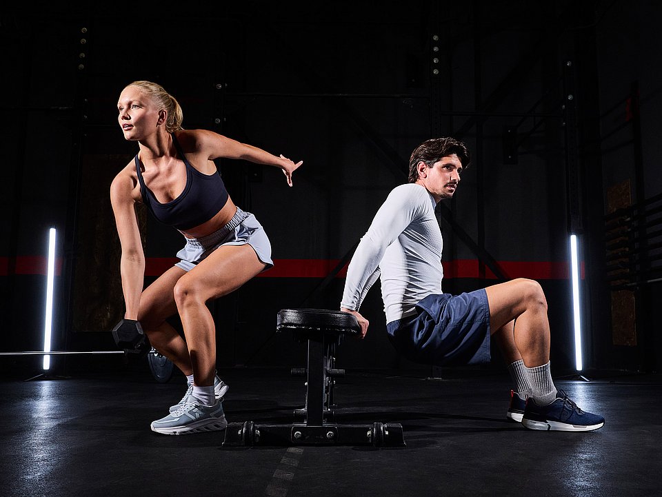 Eine Frau und ein Mann trainieren im Fitnessstudio.