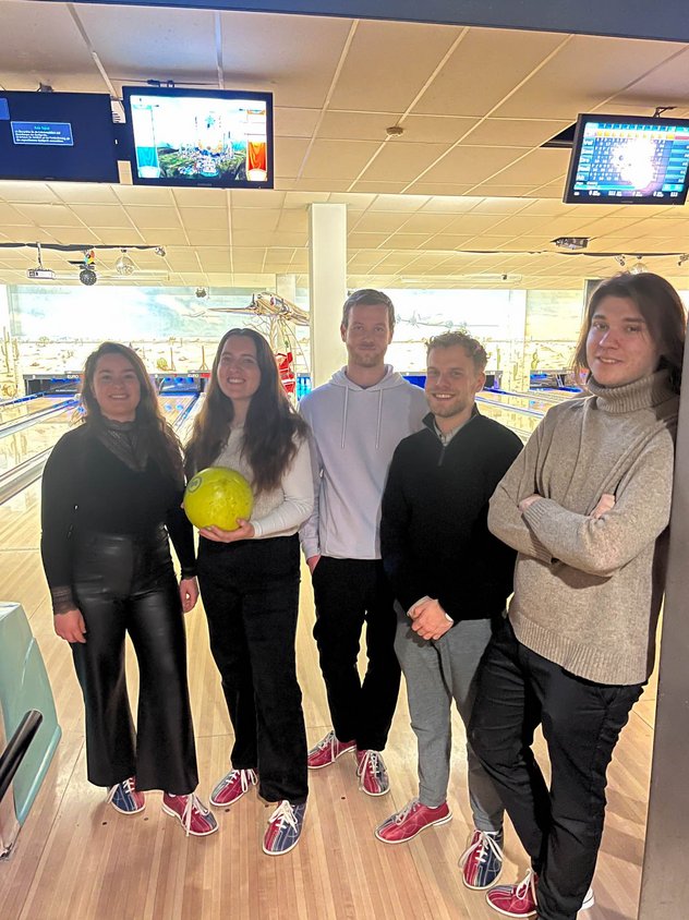 Auszubildende von Rieker stehen vor einer Bowlingbahn.