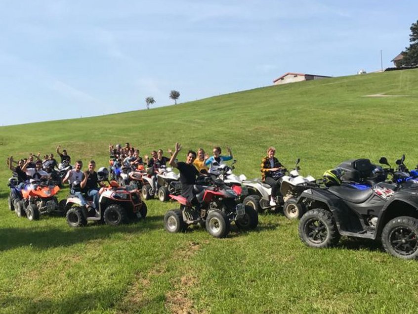 Auszubildende und dual Studierende von Rieker fahren mit Quads über eine Wiese.