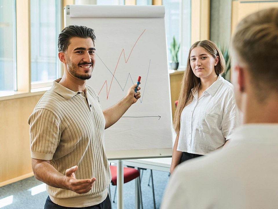 Trainees besprechen im Team ein Diagramm.