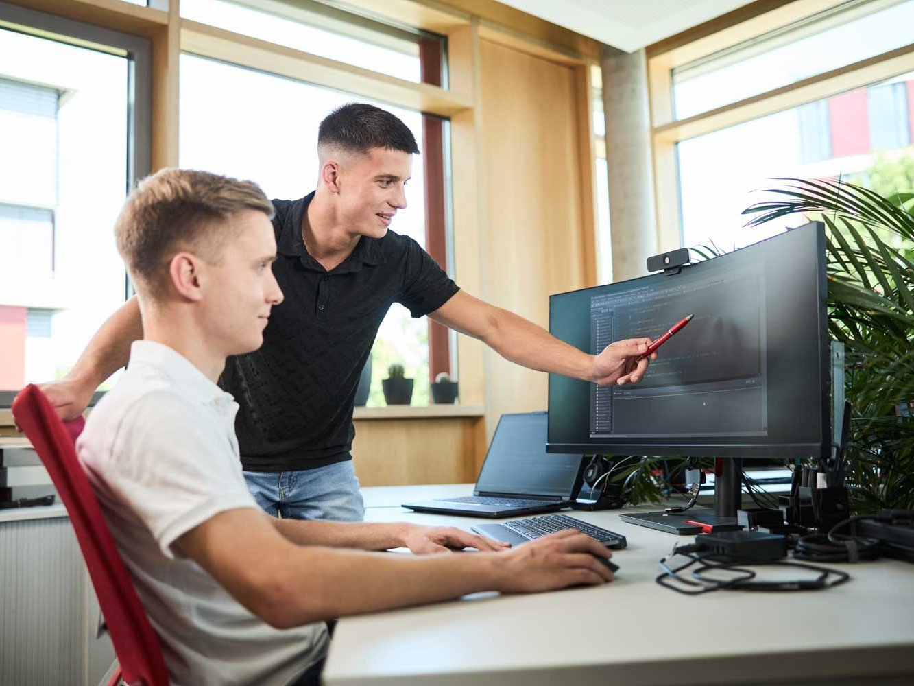 Ein Student erklärt einem anderen Studenten eine Programm auf dem Computer.