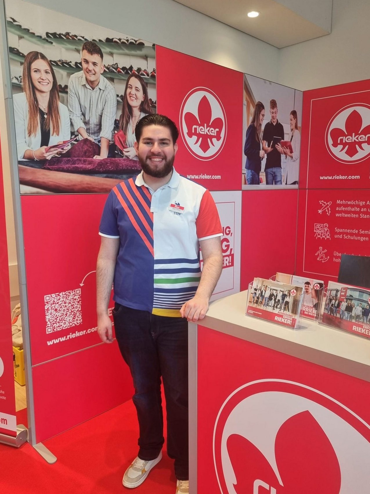 Dualer Student von Rieker steht vor einem Rieker Messestand auf einer Ausbildungsmesse.