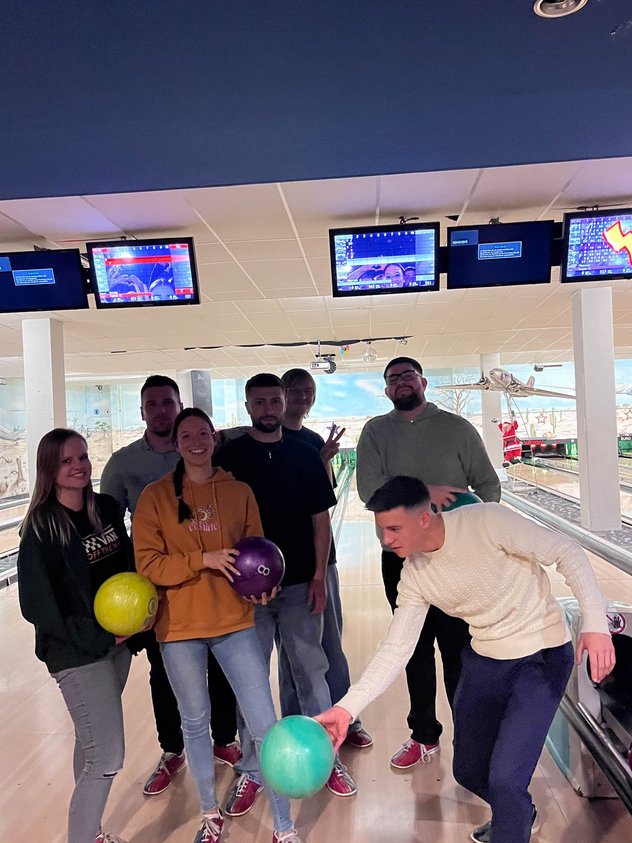Azubis beim posieren mit Bowlingkugeln in der Bowlinghalle.