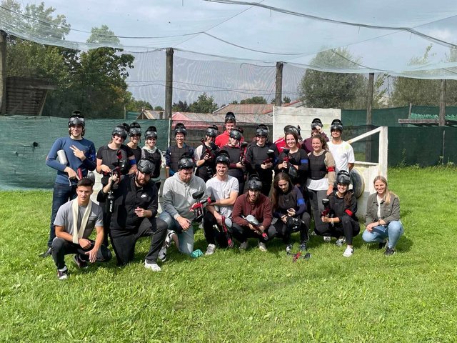Rieker Azubis posen nach einem erfolgreichen Paintbollmatch gemeinsam auf dem Spielfeld.