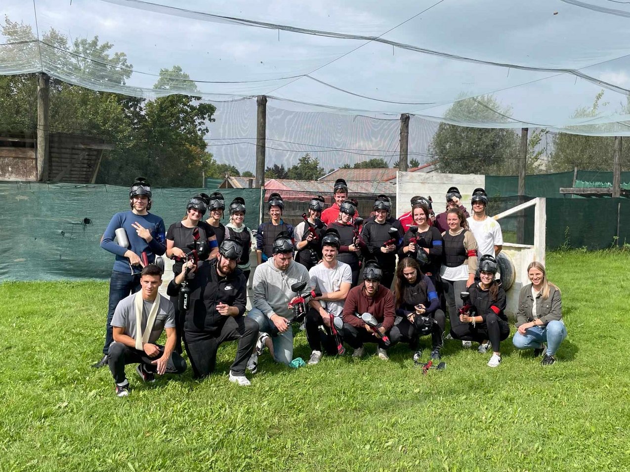 Azubis posieren für ein Gruppenbild nach einem Paintball Match.