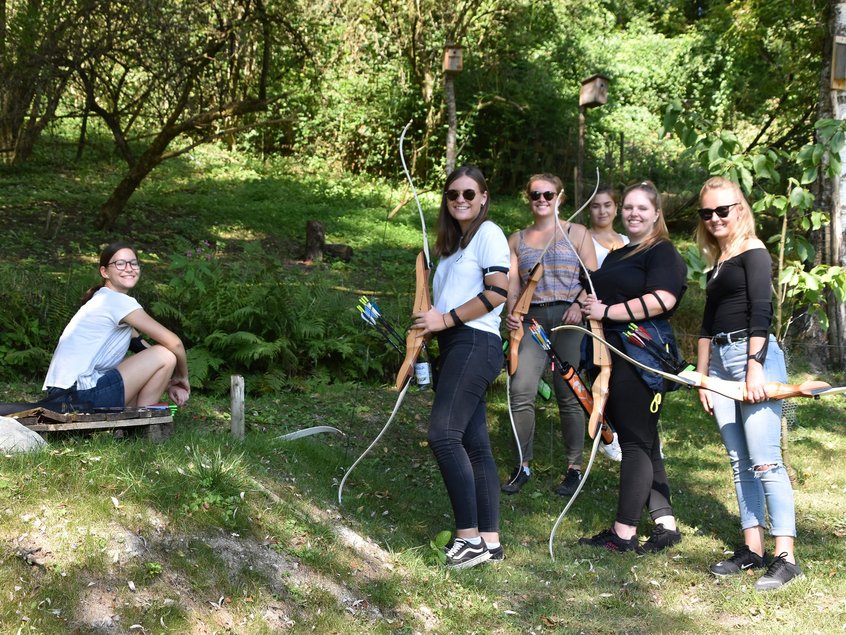 Rieker Auszubildende und dual Studierende beim Bogenschießen in einem Wald.
