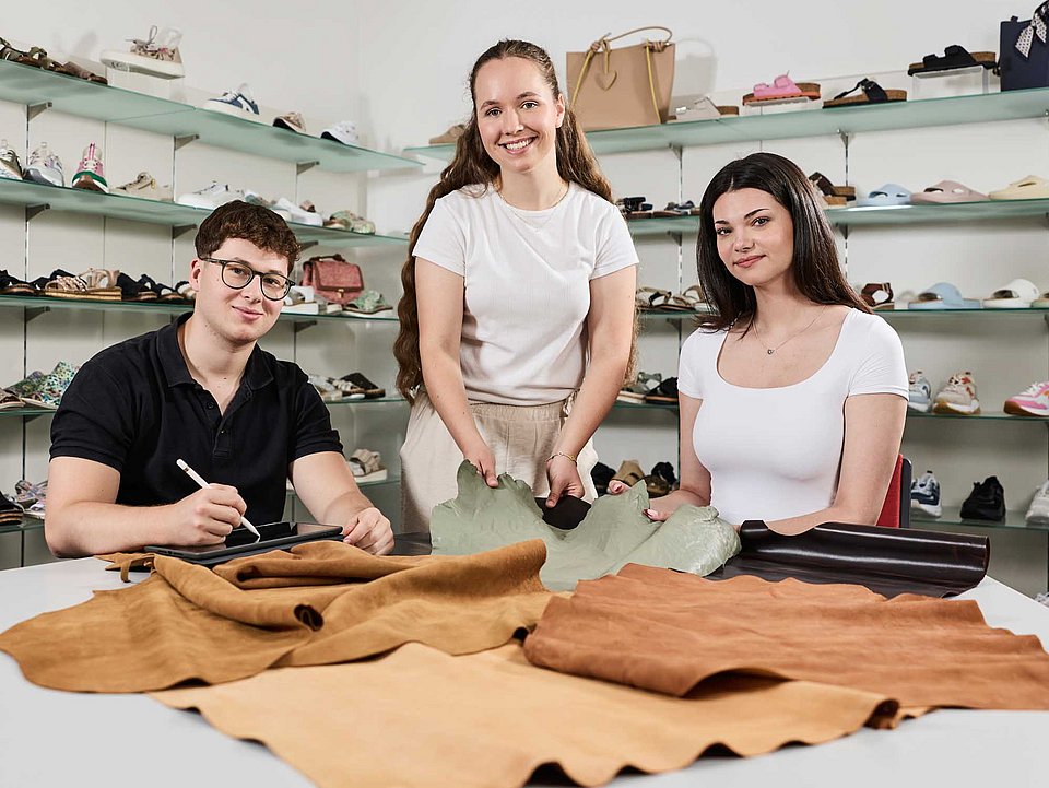 Azubis arbeiten an einem Tisch mit verschiedenen Stoff-Mustern