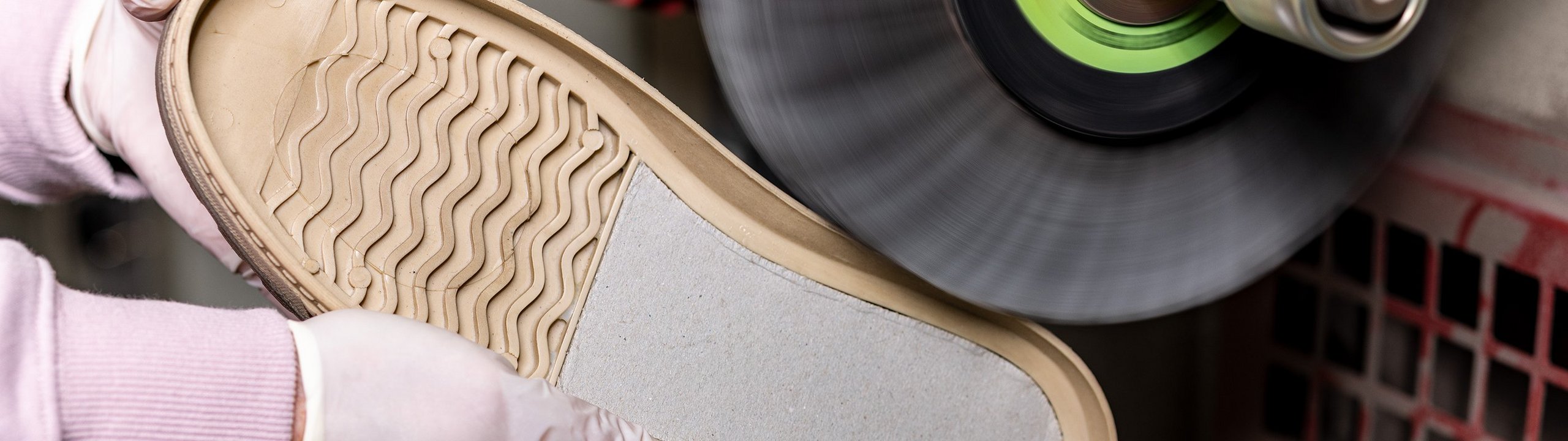 Eine Schuhsohle der Schuhmarke Rieker wird in der Produktion von Hand poliert.