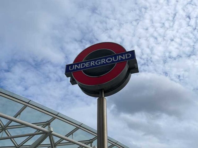 Das Schild der London Underground Station vor blauem, leicht bewölktem Himmel.