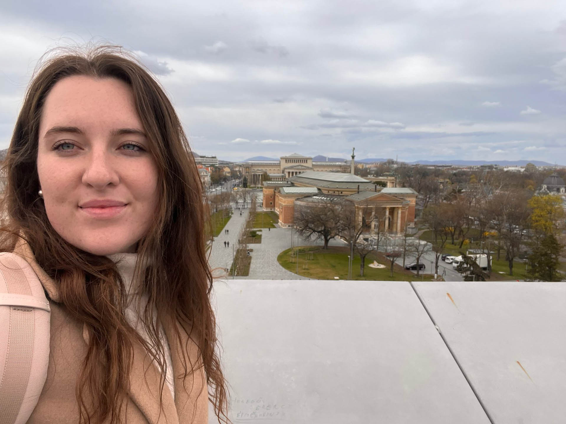 Ann-Kathrin steht auf einem Aussichtspunkt mit Blick auf eine Stadt.